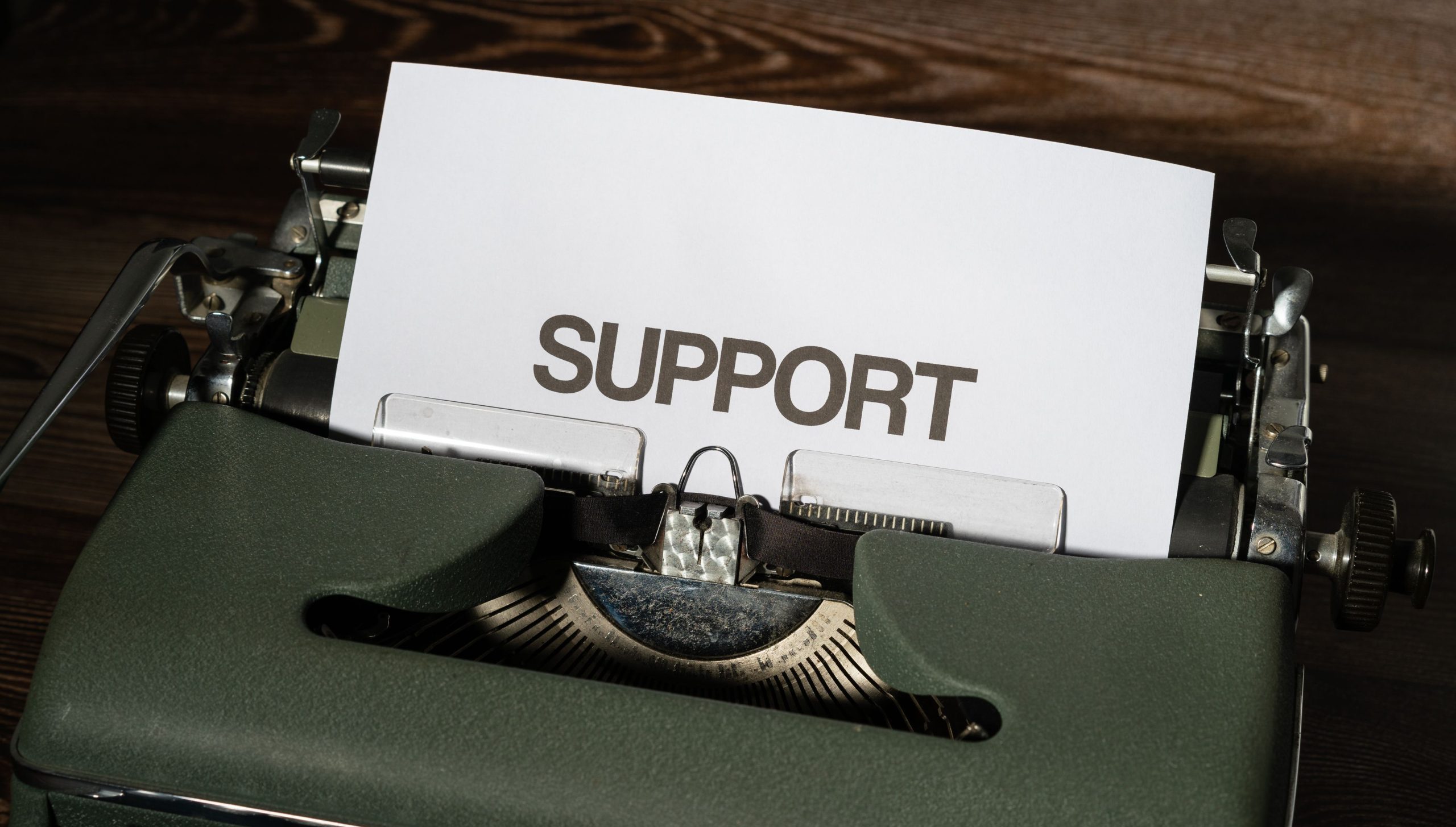 pexels photo 12220438 12220438 Close-up of vintage typewriter with 'SUPPORT' printed on paper, conveying assistance theme.